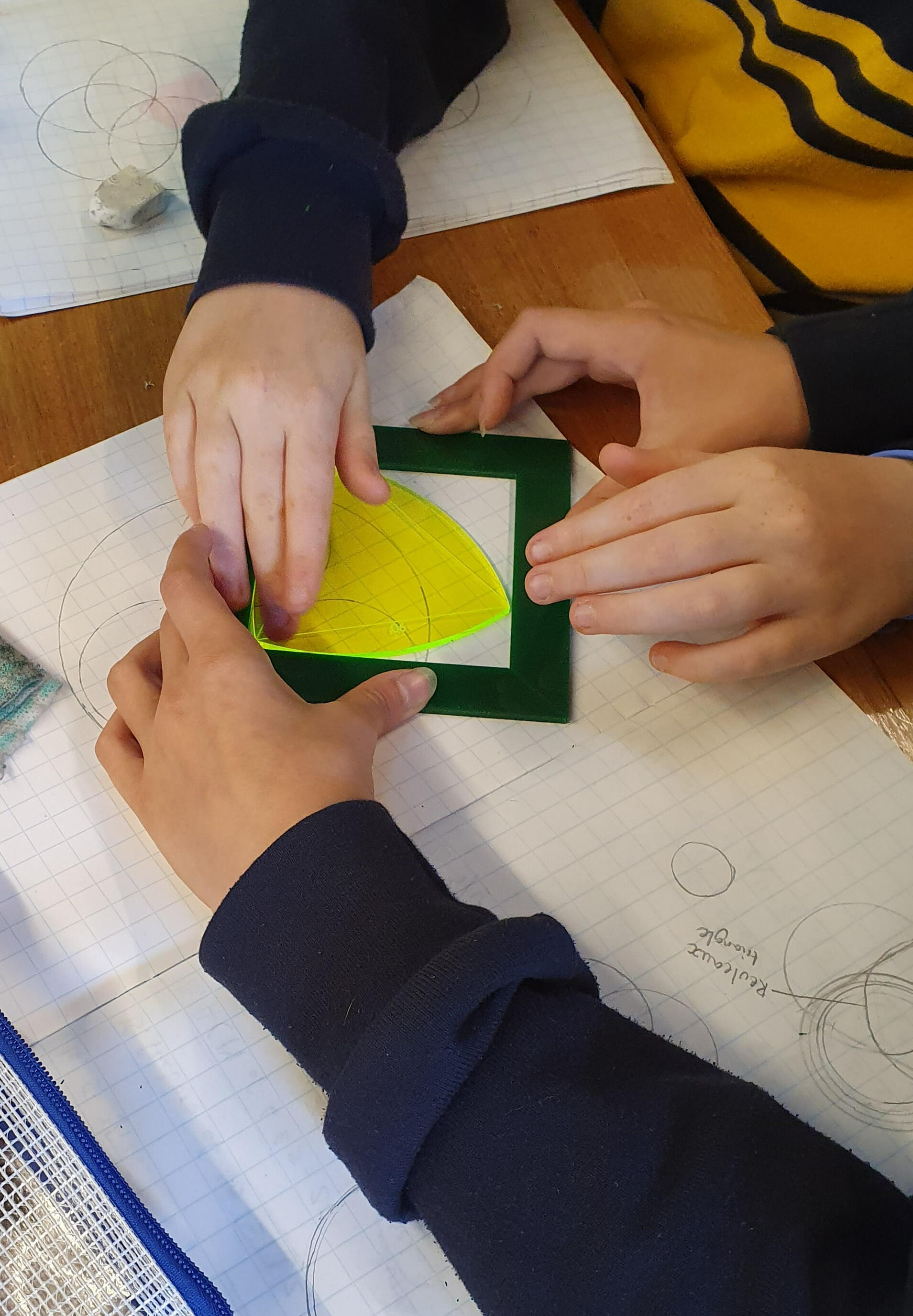 Shapes of constant width Students collaborating on a Reuleaux triangle investigation, testing a yellow cut-out shape of constant width against a square frame